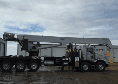 A crane lifting a large white object against a clear sky, showcasing the machinery in action.
